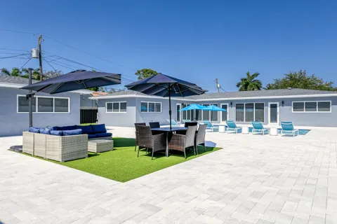a view of a patio with couches table and chairs under an umbrella