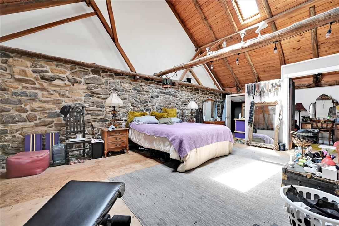 101 Conrad Road Fleetwood, PA 19522 - Photo 12 of 42 A rustic bedroom offers high beamed ceilings, exposed stone walls, and a skylight.