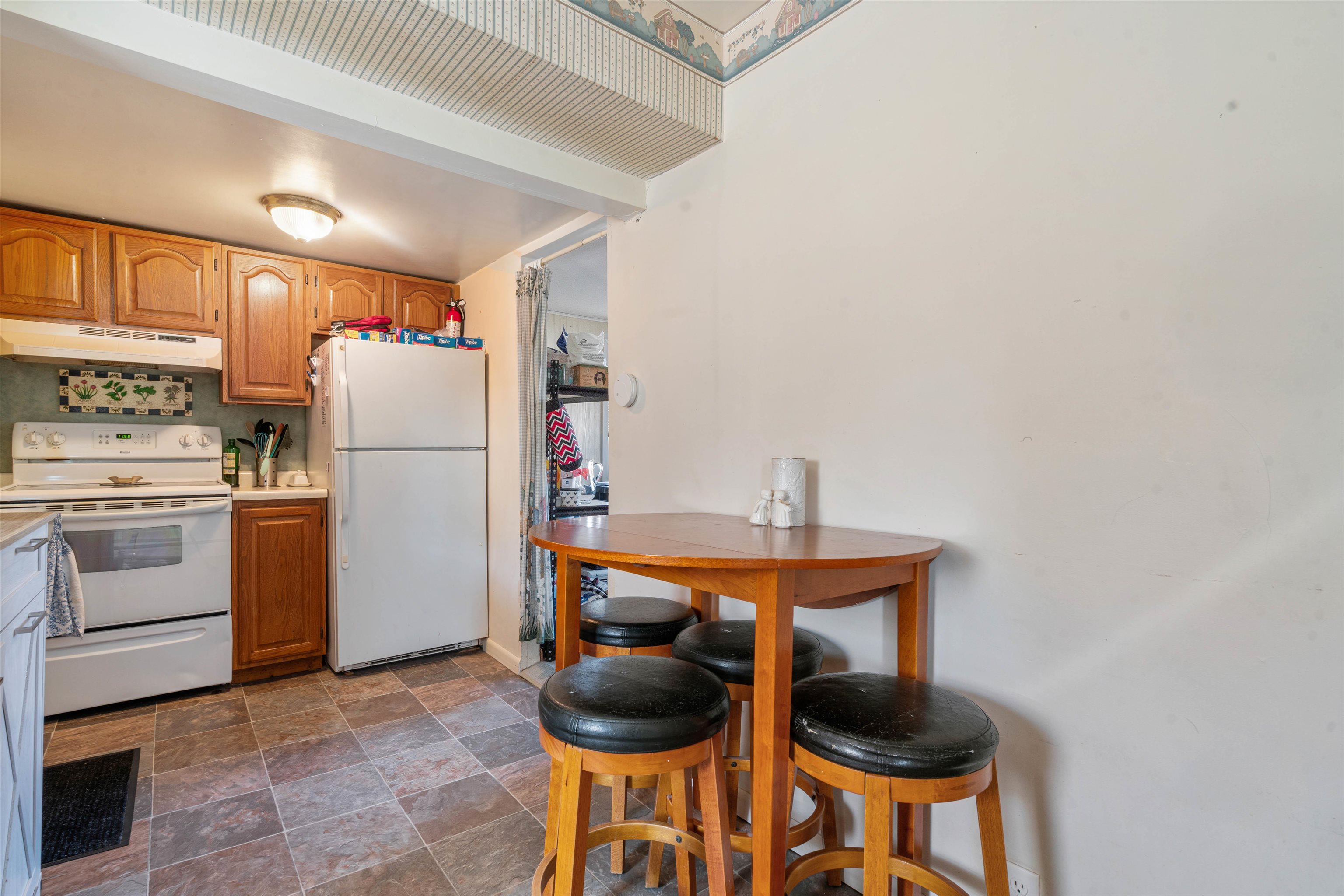 611 12th Avenue East Superior, WI 54880 - Photo 11 of 20 Kitchen featuring white appliances, light countertops, under cabinet range hood, stone finish flooring, and brown cabinets