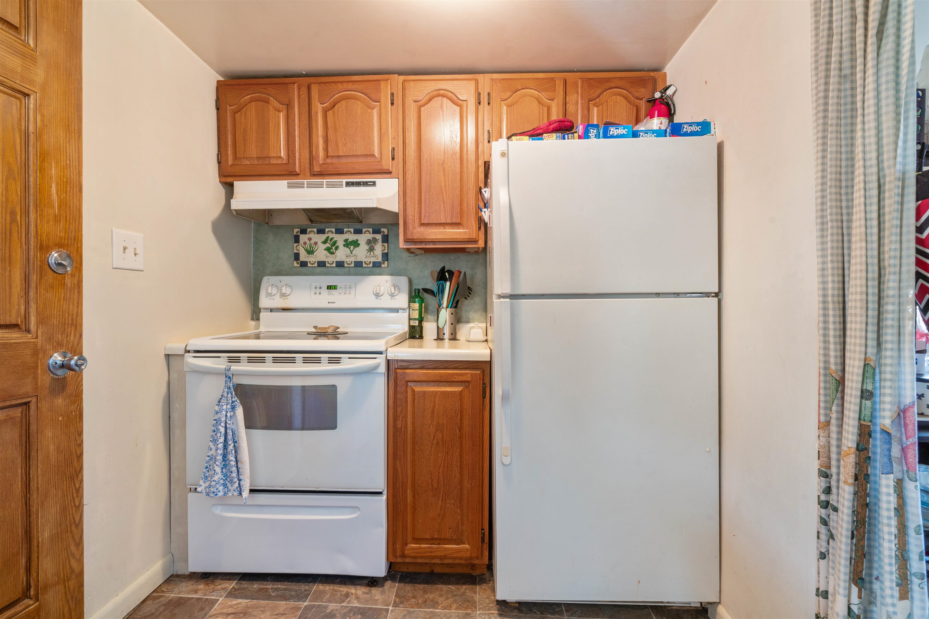 611 12th Avenue East Superior, WI 54880 - Photo 12 of 20 Kitchen with white appliances, brown cabinetry, under cabinet range hood, light countertops, and decorative backsplash