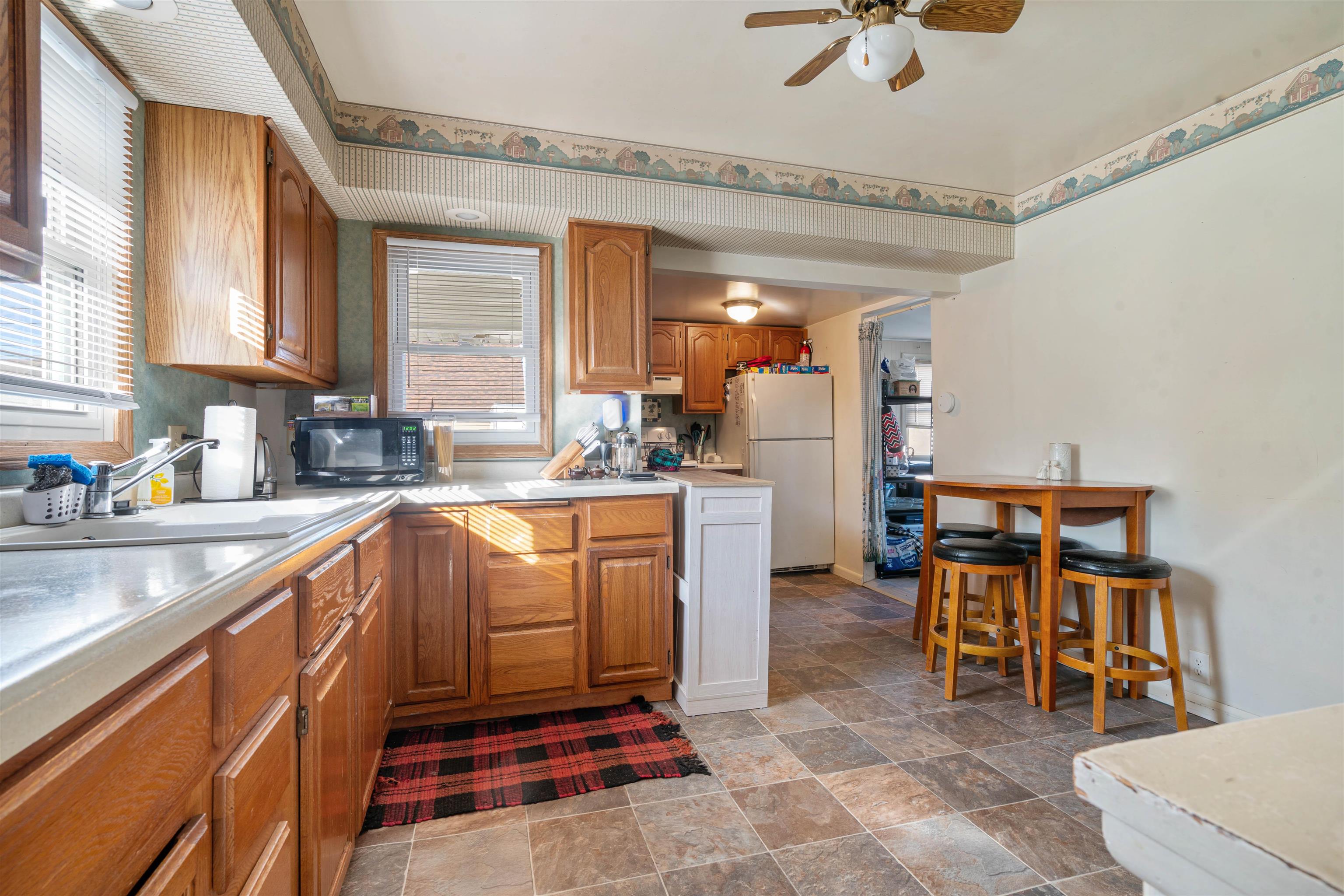 611 12th Avenue East Superior, WI 54880 - Photo 9 of 20 Kitchen with brown cabinets, light countertops, freestanding refrigerator, and black microwave
