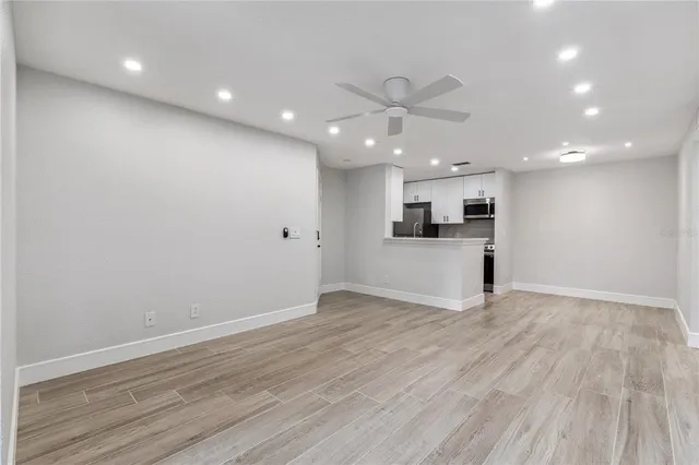 an empty room with wooden floor and kitchen view