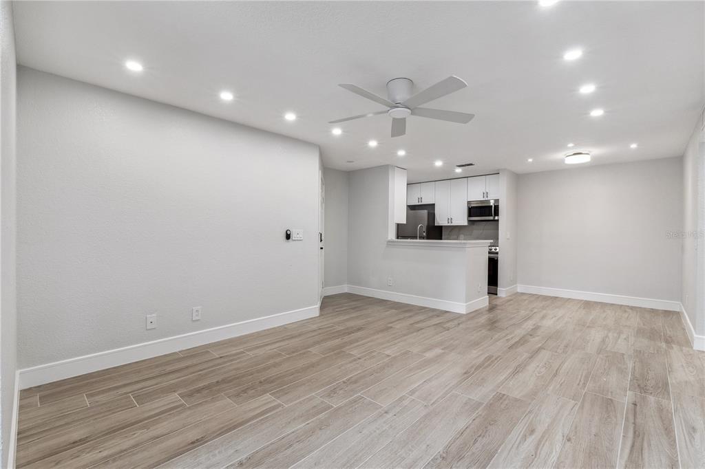 5124 Conroy Road, Unit 24 Orlando, FL 32811 - Photo 3 of 26 an empty room with wooden floor and kitchen view
