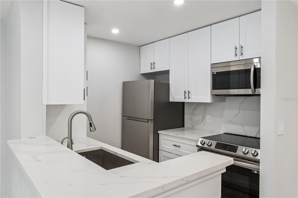 5124 Conroy Road, Unit 24 Orlando, FL 32811 - Photo 4 of 26 a kitchen with stainless steel appliances a refrigerator stove and microwave