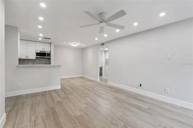 an empty room with wooden floor and a ceiling fan