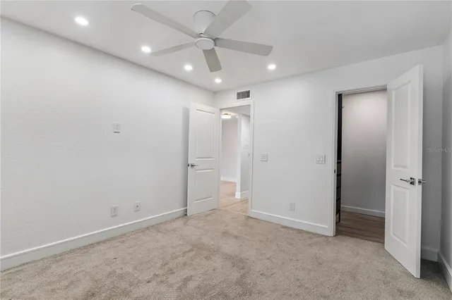 an empty room with a ceiling fan and a bathroom