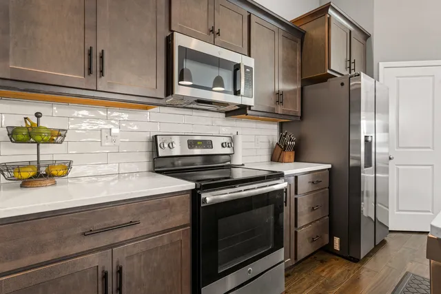 a kitchen with stainless steel appliances a sink dishwasher stove and white cabinets with wooden floor