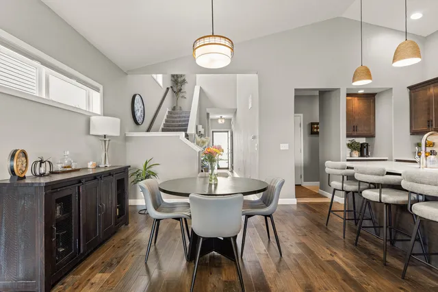 a kitchen with stainless steel appliances granite countertop a stove top oven a sink a dining table and chairs with wooden floor