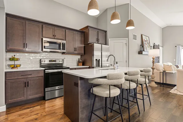 a kitchen with stainless steel appliances a dining table chairs refrigerator and cabinets