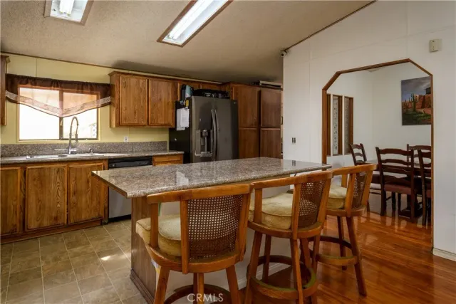 a kitchen with granite countertop a stove a sink and a refrigerator