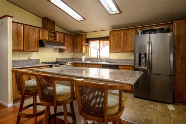 a kitchen with stainless steel appliances granite countertop a sink a microwave refrigerator and chairs