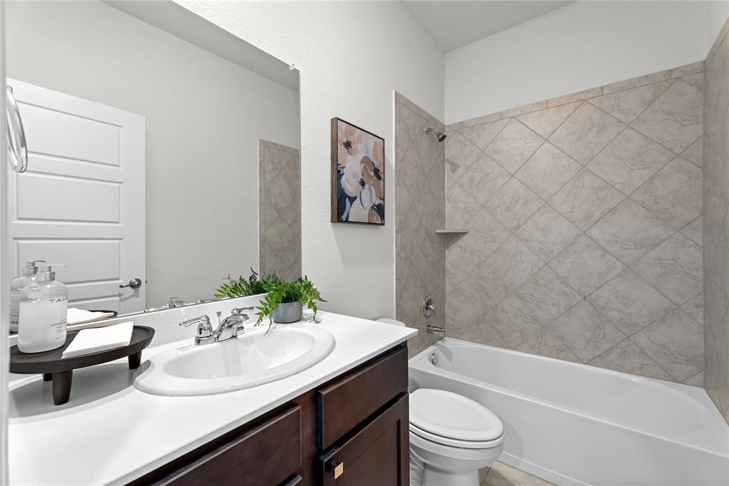 2908 Frio Road Little Elm, TX 75068 - Photo 18 of 26 Bathroom featuring a white vanity countertop with an integrated sink, dark wood-finish cabinetry, chrome fixtures, and a bathtub with diamond-patterned wall tile