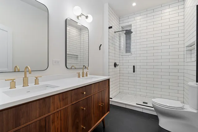 a bathroom with a double vanity sink toilet and shower