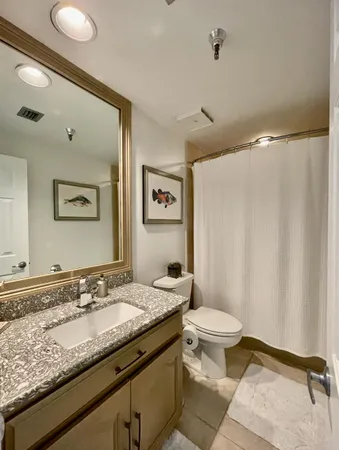 a bathroom with a granite countertop sink mirror vanity and toilet