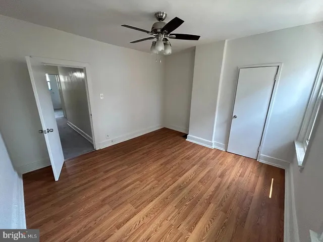 an empty room with wooden floor and a ceiling fan