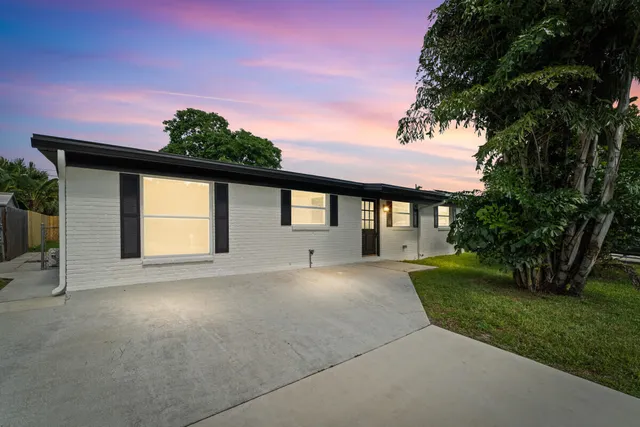 a front view of a house with a garden and trees