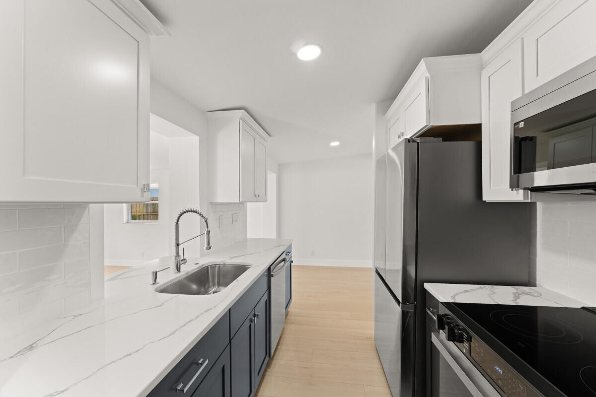 3797 Bahama Road Palm Beach Gardens, FL 33410 - Photo 5 of 27 a kitchen with stainless steel appliances a sink cabinets and wooden floor