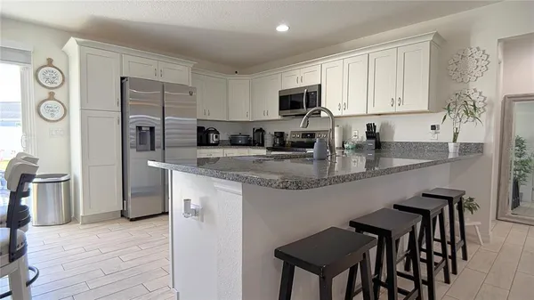 a kitchen with stainless steel appliances granite countertop a stove top oven a refrigerator a sink and dishwasher with wooden floor