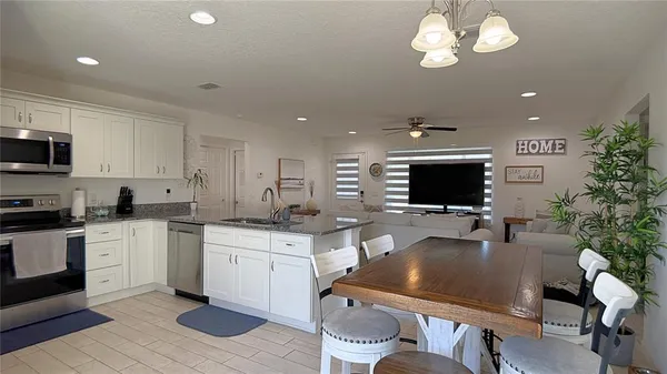 a kitchen with stainless steel appliances a stove a sink a microwave a dining table and chairs