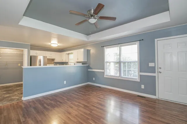 a view of an empty room with window and wooden floor