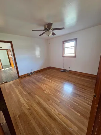 an empty room with wooden floor fan and windows