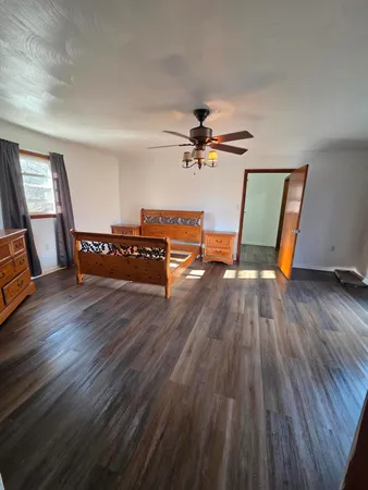 a view of an empty room with wooden floor and a ceiling fan
