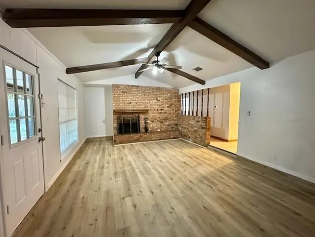 a view of empty room with wooden floor and fireplace
