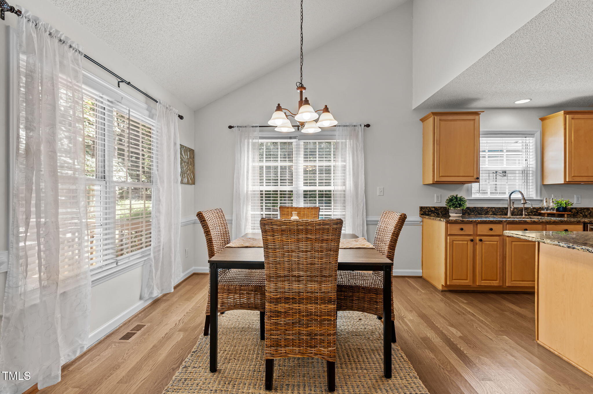 11924 Larka Court Raleigh, NC 27613 - Photo 10 of 44 a dining room with wooden floor a chandelier a glass table and chairs