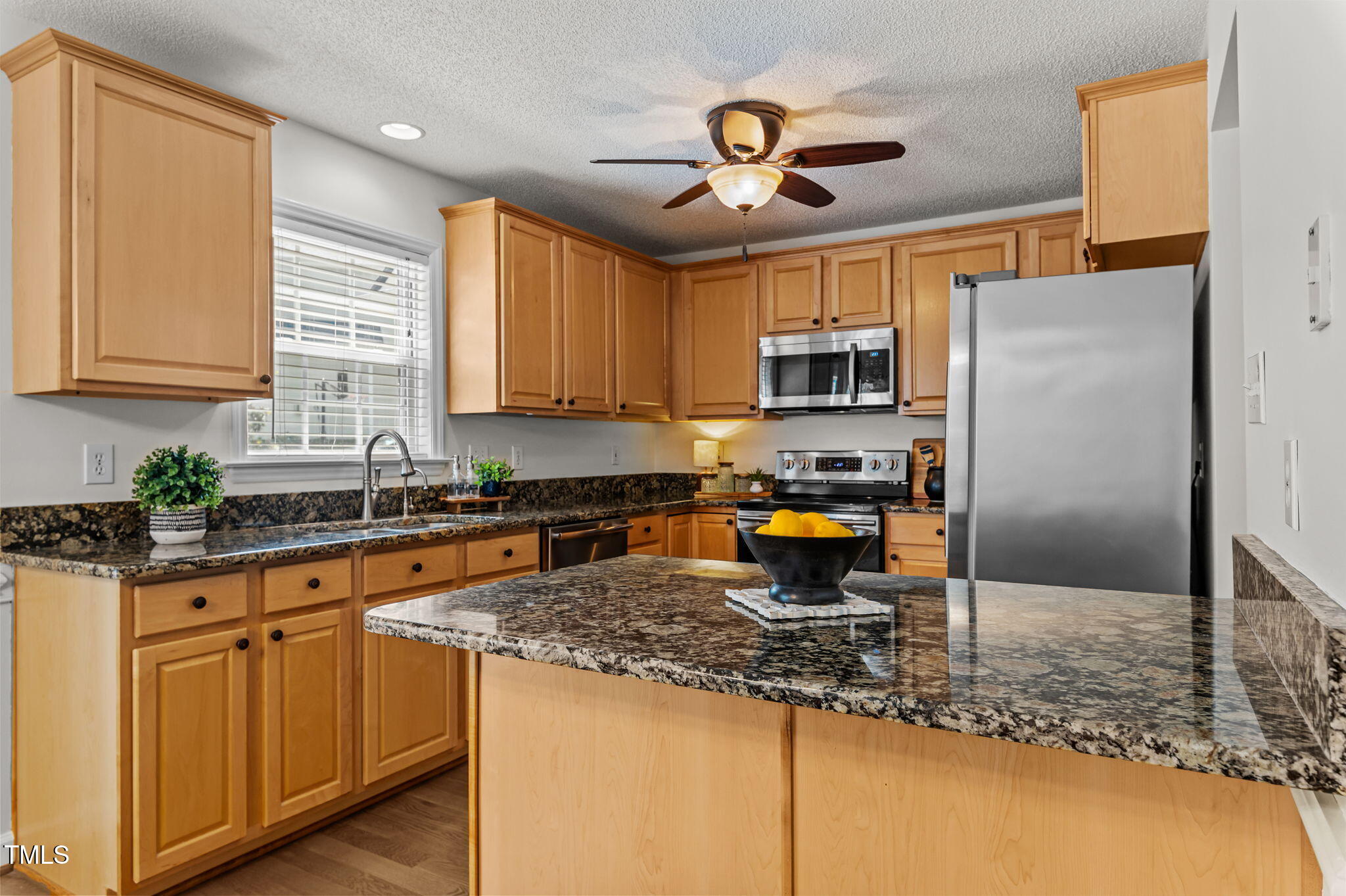 11924 Larka Court Raleigh, NC 27613 - Photo 12 of 44 a kitchen with stainless steel appliances granite countertop a stove a sink a refrigerator a microwave oven with cabinets and wooden floor