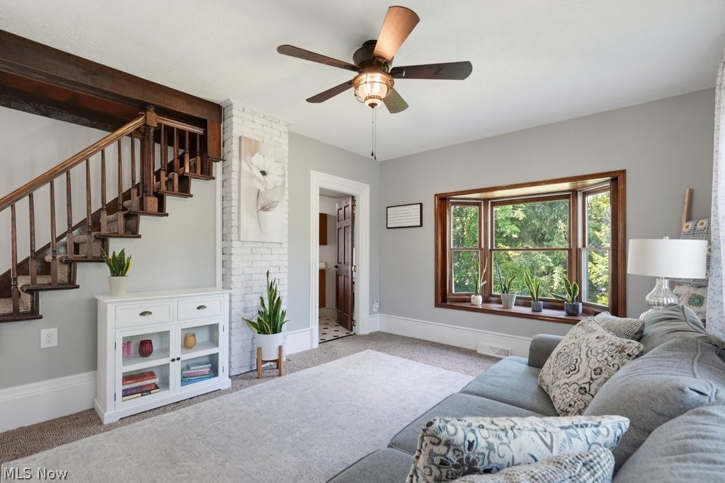 23055 Snell Road Columbia Station, OH 44028 - Photo 21 of 50 Spacious room featuring a prominent wooden staircase with dark wood banister, a bay window with wood trim, and a ceiling fan with integrated lighting