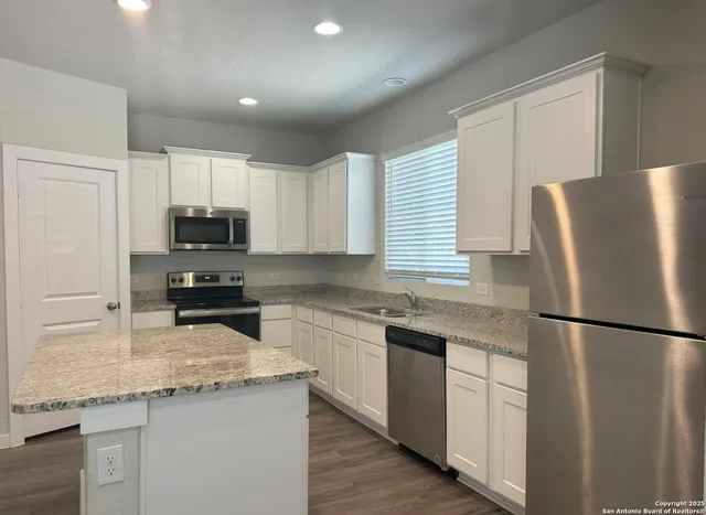 a kitchen with stainless steel appliances granite countertop a refrigerator sink stove microwave and cabinets