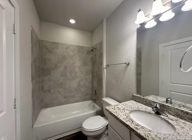a bathroom with a granite countertop sink toilet a shower and a mirror