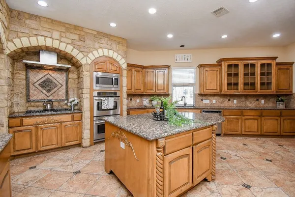 a kitchen with stainless steel appliances granite countertop a stove a sink and a microwave