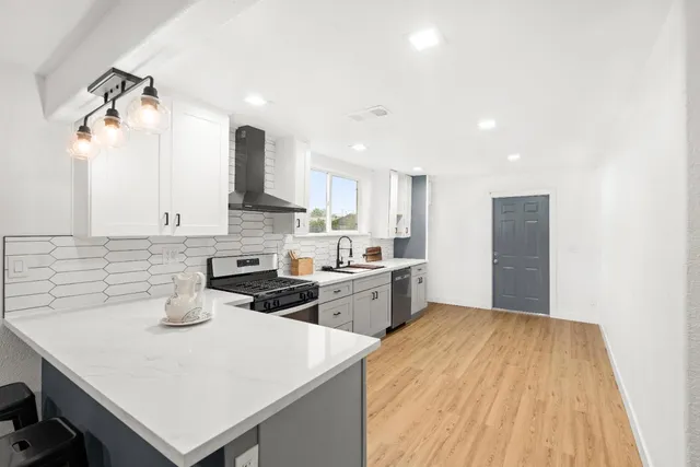 a large kitchen with a lot of counter space and wooden floor