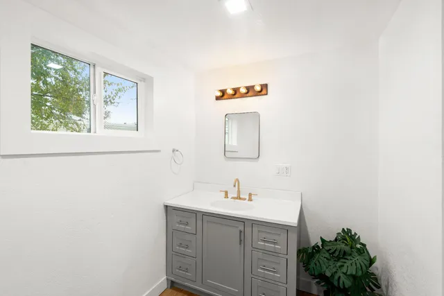 a bathroom with a granite countertop toilet a sink and a mirror