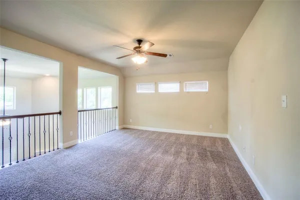 an empty room with chandelier fan and windows