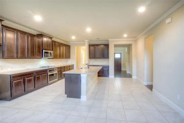 a large kitchen with a large counter top stainless steel appliances and cabinets