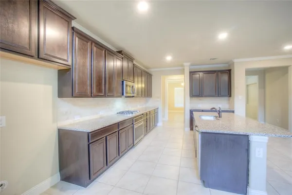 a large kitchen with a large counter top stainless steel appliances and cabinets