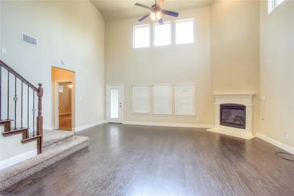an empty room with wooden floor fireplace and windows