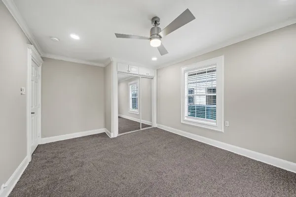 an empty room with windows and ceiling fan