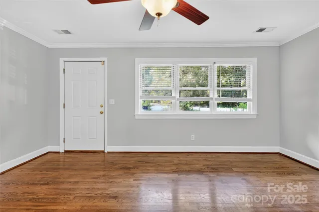 a view of an empty room with wooden floor and a window