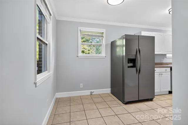 a view of a refrigerator in kitchen and an empty room in wooden floor