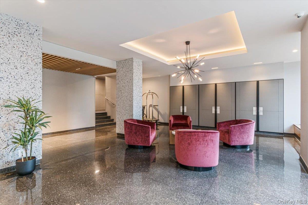 17-85 215th Street, Unit 1E Queens, NY 11360 - Photo 13 of 34 a living room with furniture gym equipment and a chandelier