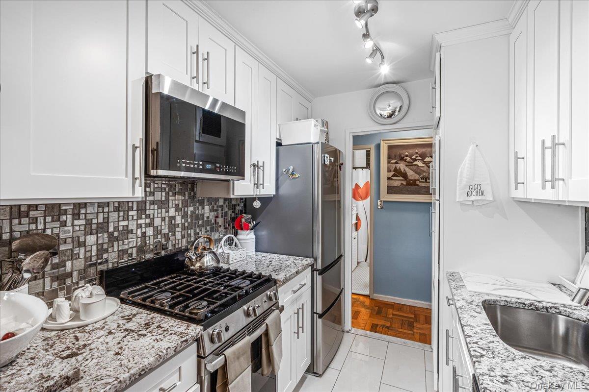 17-85 215th Street, Unit 1E Queens, NY 11360 - Photo 6 of 34 a kitchen with stainless steel appliances granite countertop a sink stove and refrigerator