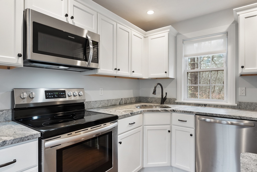 166 Parker Street, Unit 4 Maynard, MA 01754 - Photo 11 of 37 a kitchen with stainless steel appliances granite countertop a sink a stove a microwave and cabinets