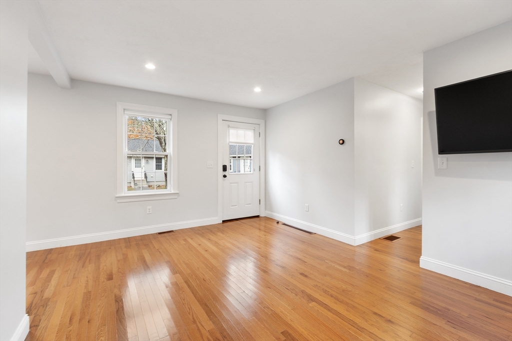 166 Parker Street, Unit 4 Maynard, MA 01754 - Photo 14 of 37 a view of an empty room with wooden floor and a flat screen tv