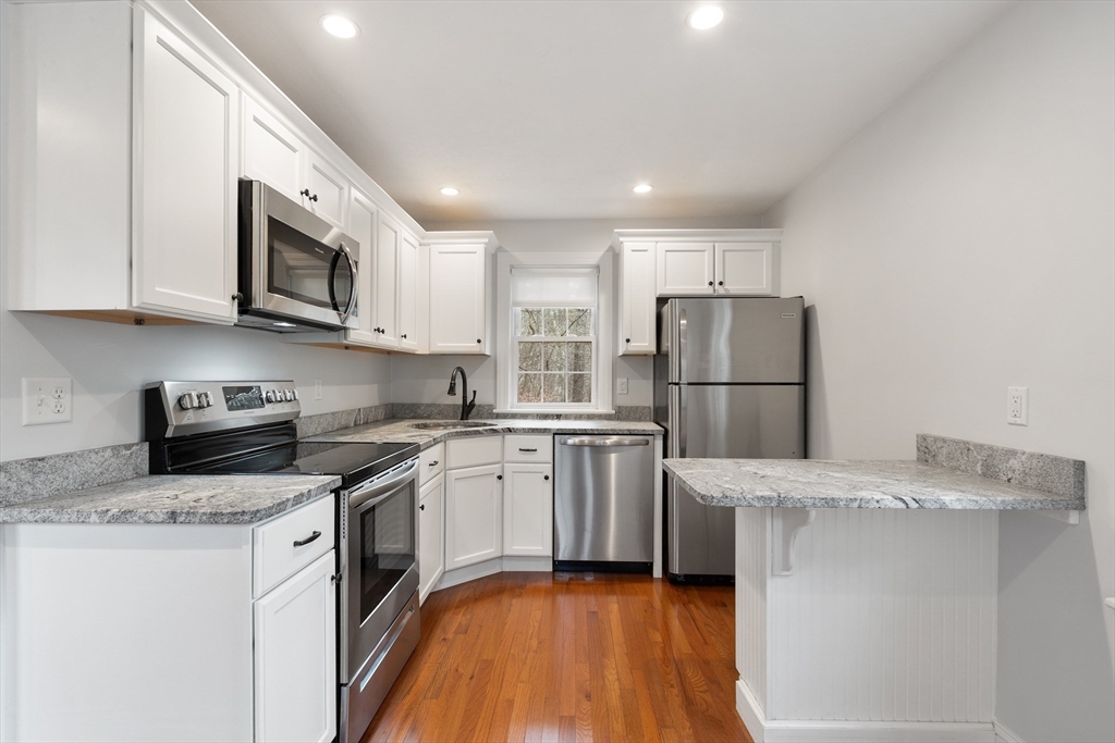 166 Parker Street, Unit 4 Maynard, MA 01754 - Photo 9 of 37 a kitchen with a sink a microwave a refrigerator and cabinets