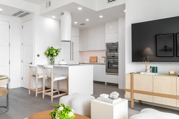 a living room with furniture a flat screen tv and kitchen view