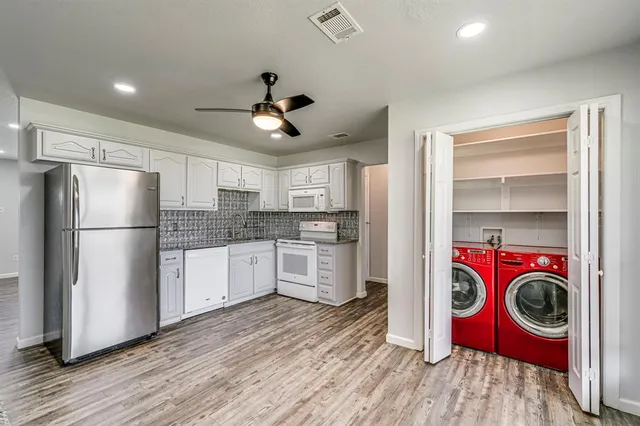 a kitchen with stainless steel appliances granite countertop a refrigerator a stove and wooden floors