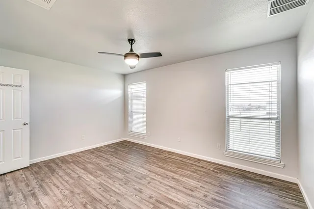 a view of an empty room with a window and wooden floor